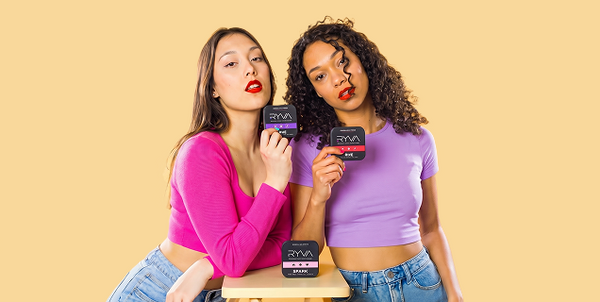 Two women holding and showing off products with visible branding against a beige background