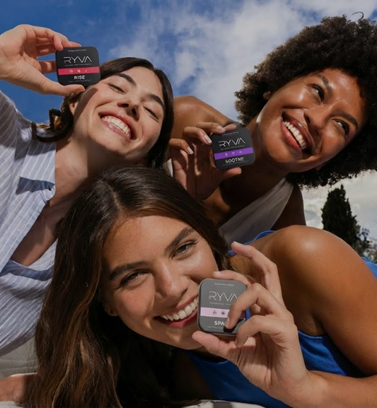Three women holding small electronic devices with 'RYVA' branding against a blue sky.